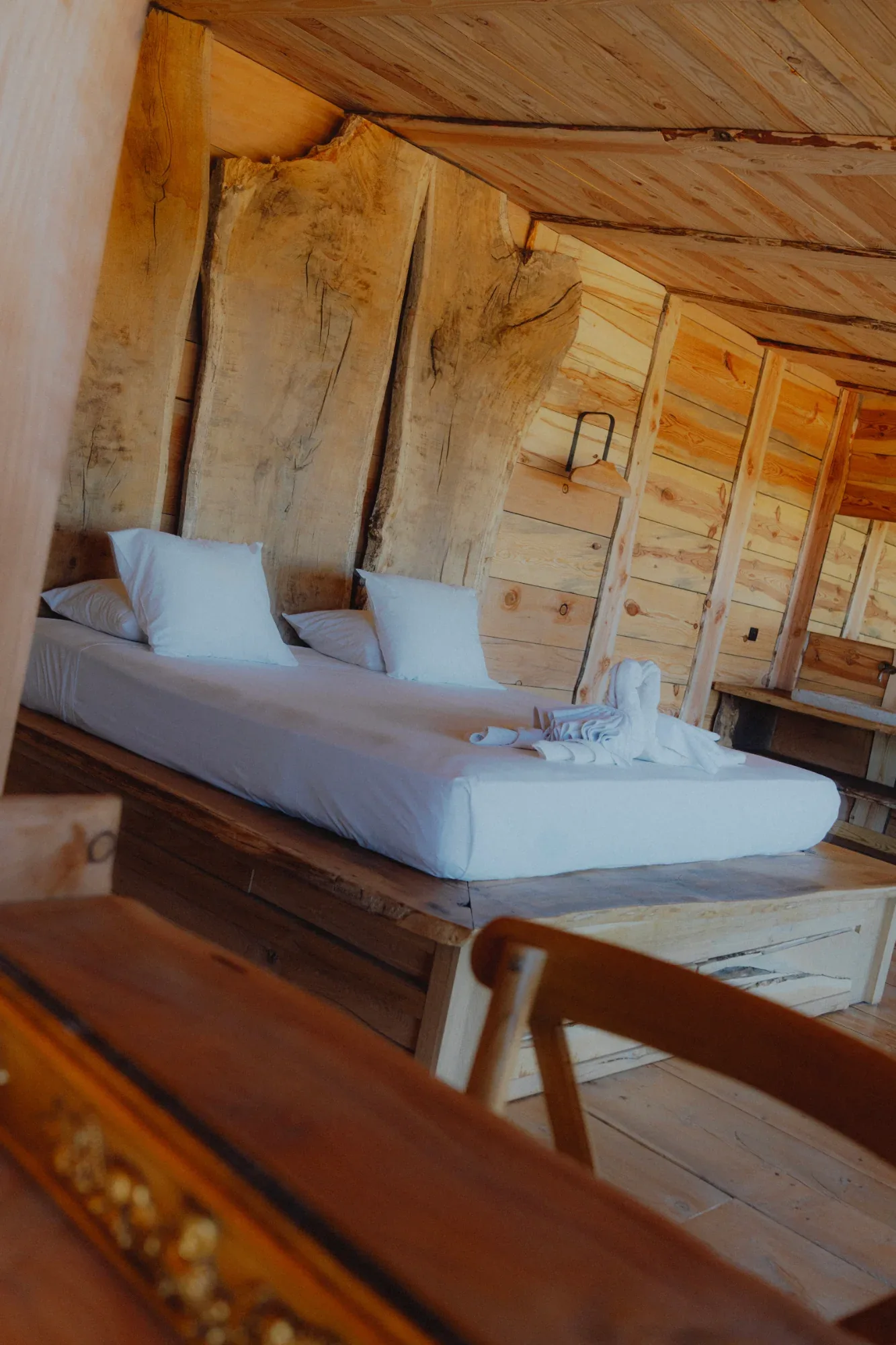 Chambre de la suite aux murs de bois brut, hébergement du domaine